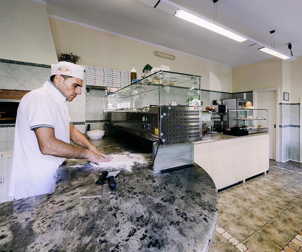 Il pizzaiolo lavora l’impasto sul bancone di granito