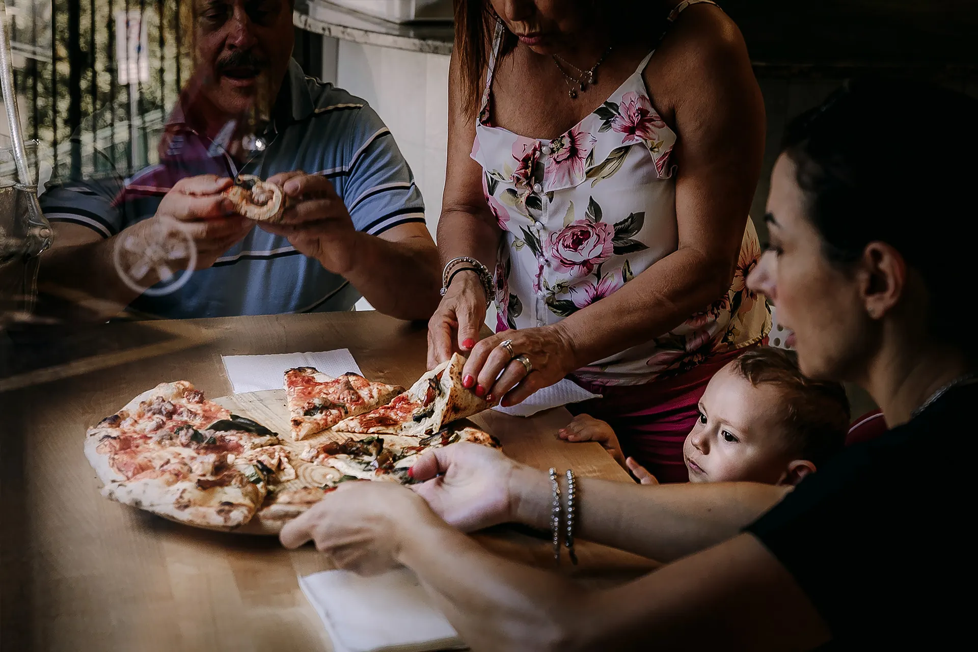 Una famiglia a tavola, con un bambino, divide una pizza